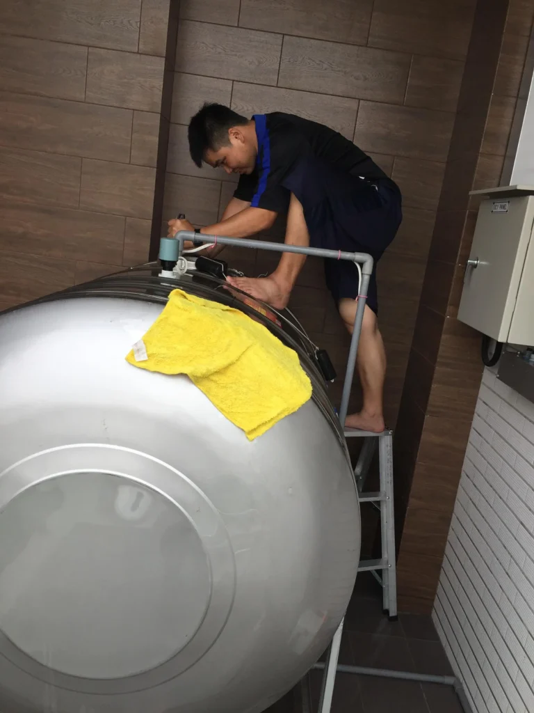 IMG_5081 一個清潔人員用一個梯子站在水塔旁邊清洗水塔